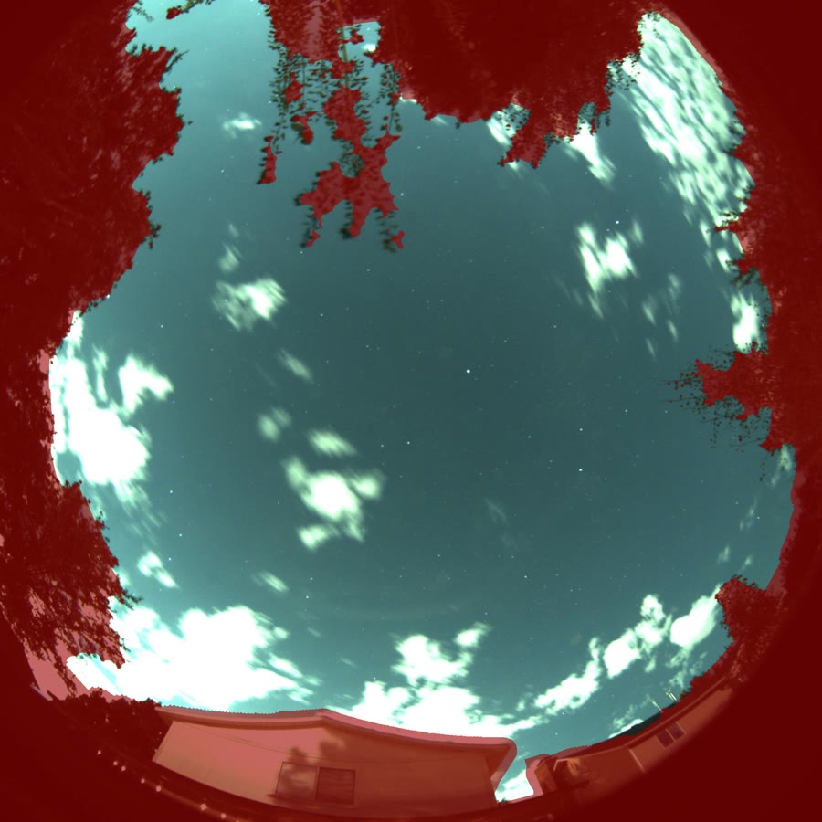 The automatic sky mask on a real night frame: everything red — trees, rooflines, the mount of the camera itself — is excluded from cloud detection, leaving only true sky. The clouds drifting through the open region stay unmasked — they are weather, not horizon